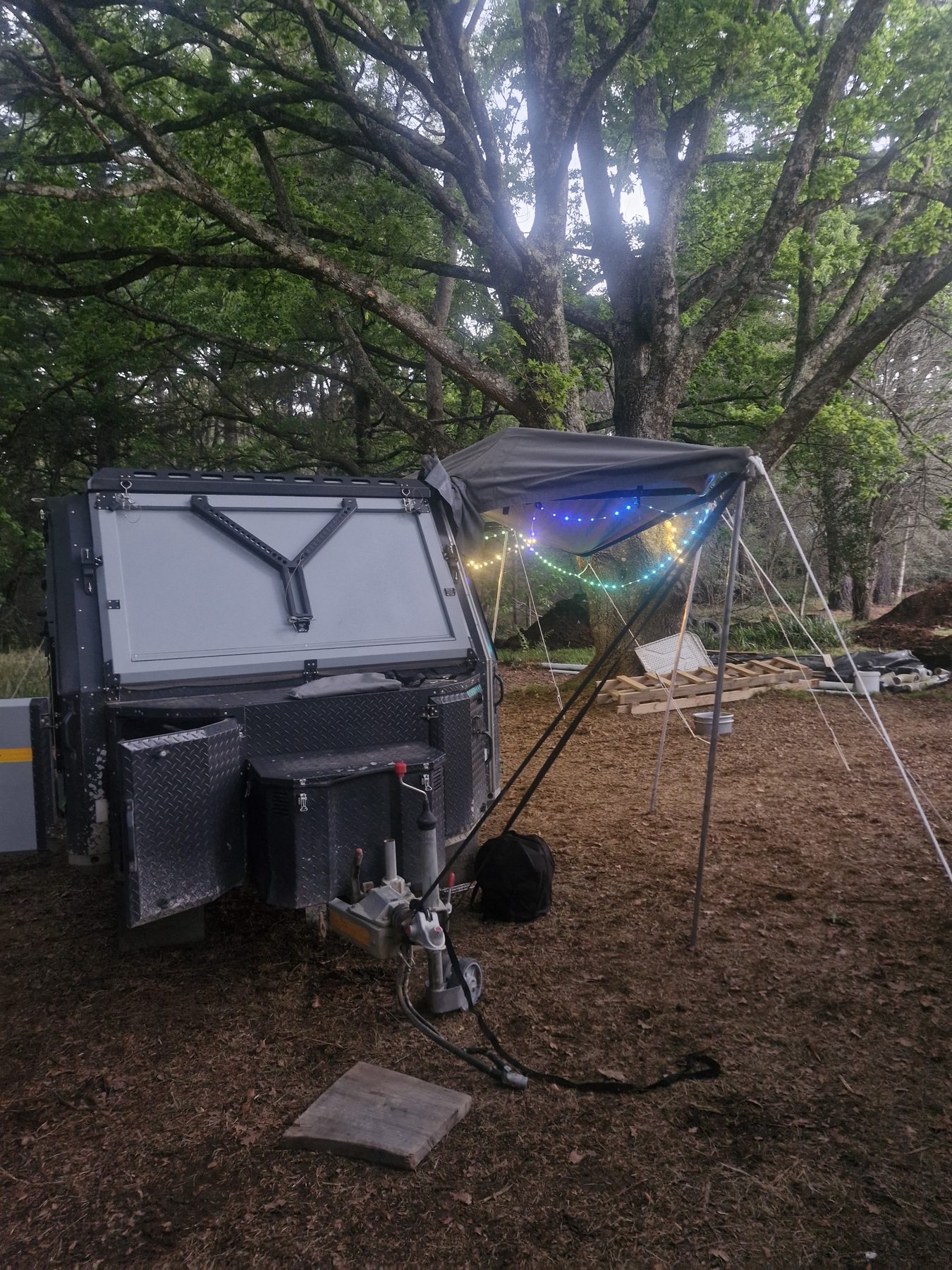 Off-road caravan with awning and fairy lights under oak trees at Maylodge campsite