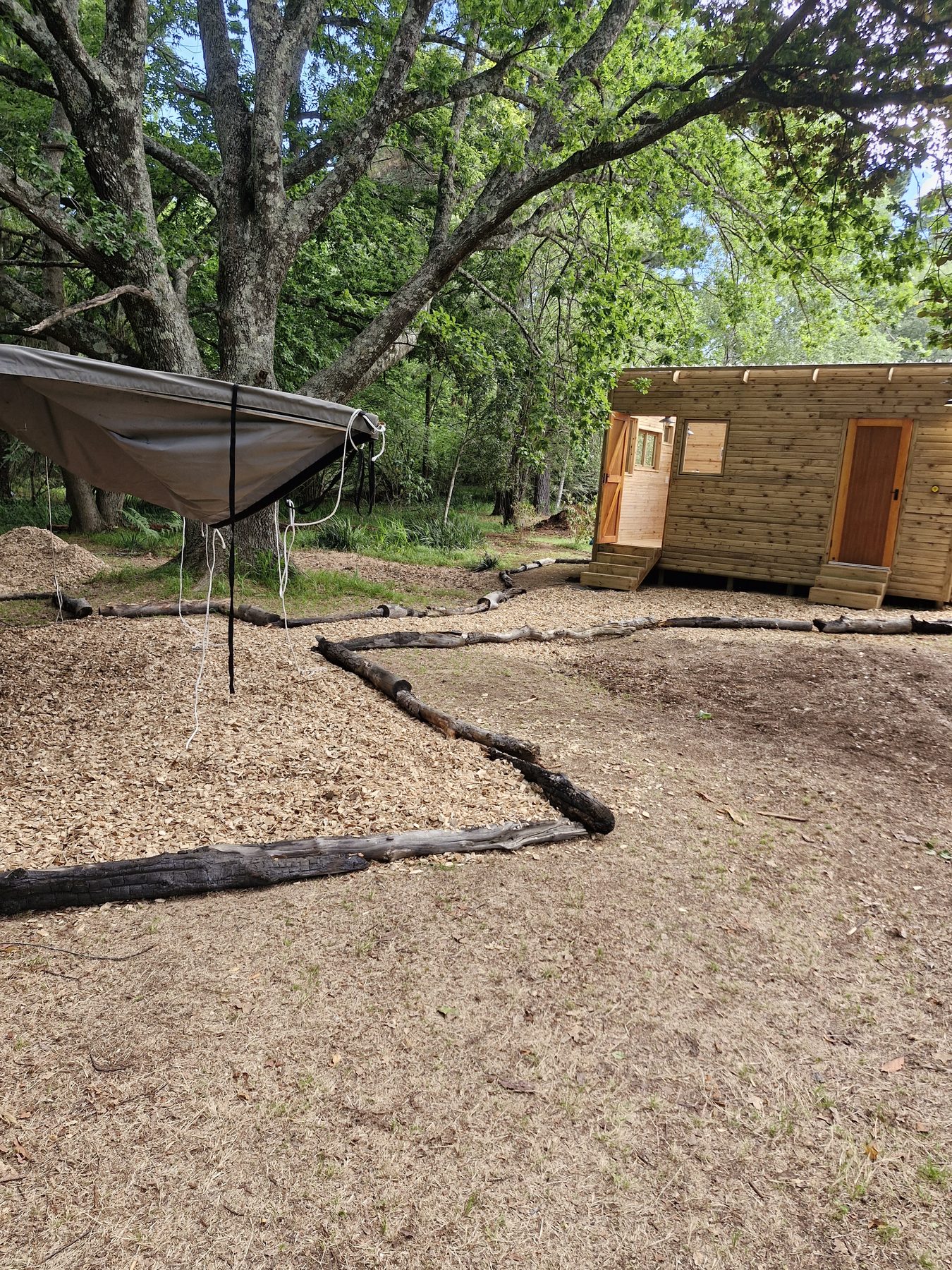Hammock and shade sail beside a private timber bathroom hut at Maylodge campsite