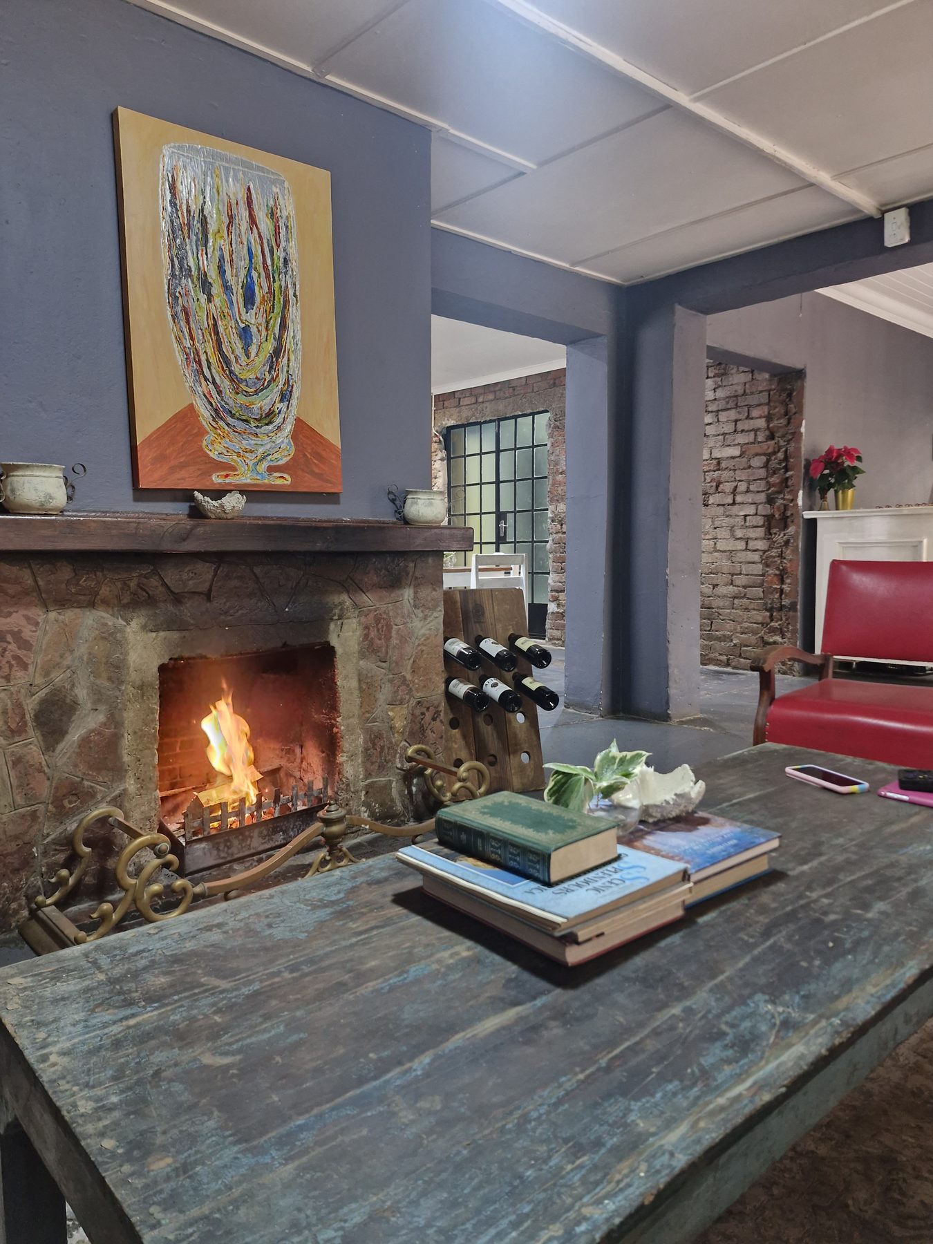 The fireplace lit in the lounge at Happy Hogs, with books on a scrubbed table