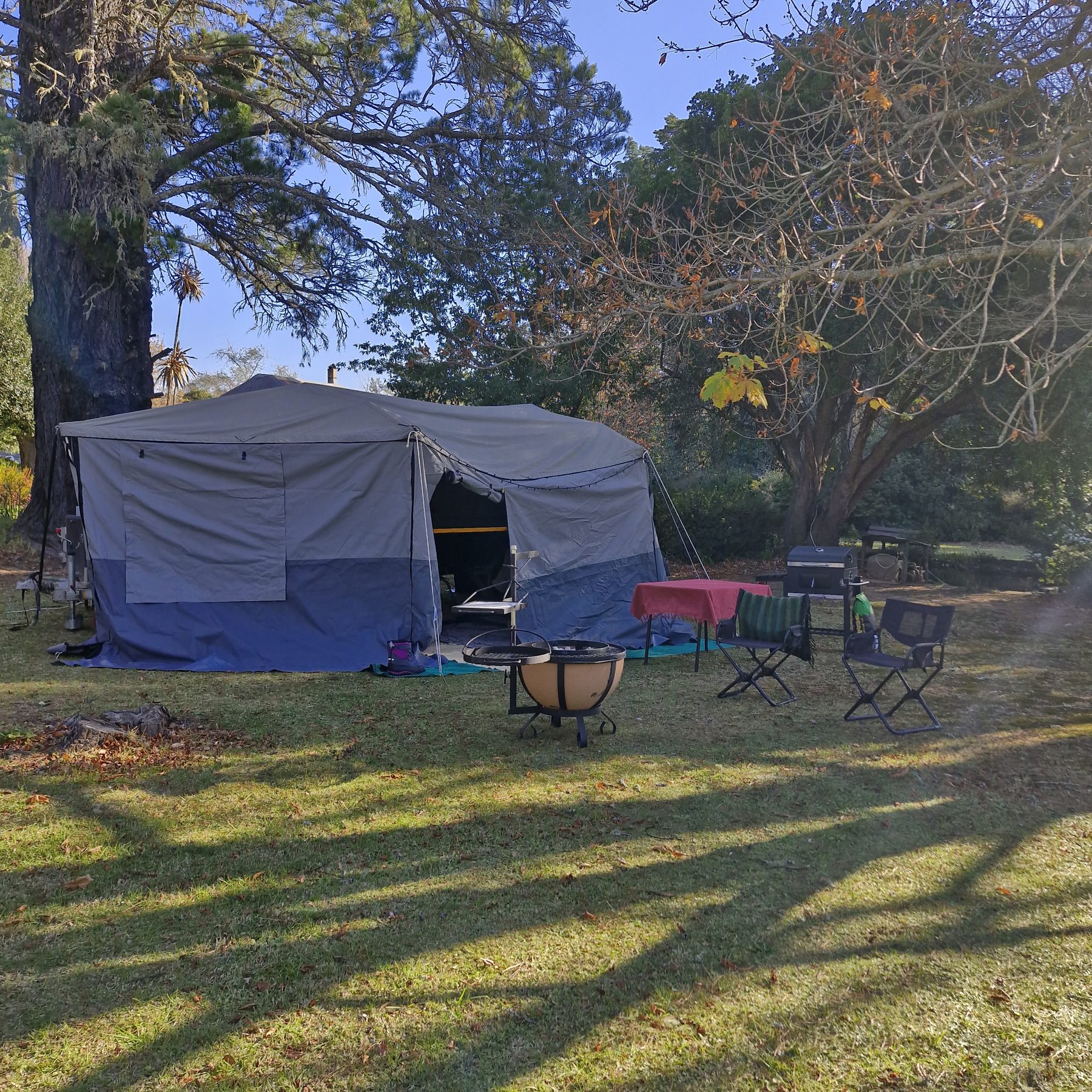 A canvas trailer tent pitched on the open lawn under the trees at Maylodge campsite in Hogsback